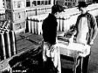 Douilles de fusil-mitrailleur Bren. Des ouvriers appliquent une couche de peinture antirouille sur des douilles à la fabrique de munitions National Steel Car Corporation Ltd Dec. 1939