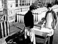Douilles de fusil-mitrailleur Bren. Des ouvriers appliquent une couche de peinture aux douilles à la fabrique de munitions National Steel Car Corporation Ltd. pour les rendre résistantes à la rouille Dec. 1939