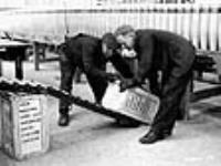 Des ouvriers chargent des caisses de munitions pour fusil-mitrailleur Bren sur une rampe à l'usine de munitions de la National Steel Car Corporation Ltd Dec. 1939