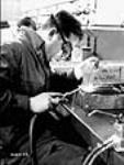 Un ouvrier soude des chargeurs de fusil-mitrailleur Bren dans une entreprise canadienne Dec. 1939