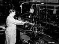 Dans une fabrique canadienne, un opérateur utilise une machine pour façonner des lames-chargeurs de fusils-mitrailleurs Bren Dec. 1939