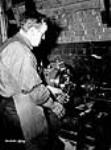 Un ouvrier règle un tour utilisé dans la fabrication de fusils-mitrailleurs Bren July 1940