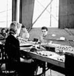 Des ouvriers et des ouvrières vérifient des fusées dans une usine canadienne Aug. 1940