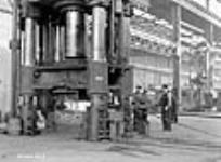 À l'aciérie Sorel Steel, des ouvriers conduisent une énorme presse à forger et transforment un bloc de six pieds en une ébauche de tube de canon de 14 pieds Dec. 1940