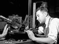Un outilleur vérifie l'angle d'un outil de coupe utilisé pour aléser l'âme d'un canon à l'usine Sorel Steel Dec. 1940