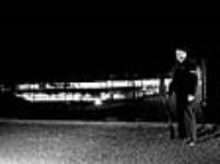 Night watchman stands guard with a gun outside the John Inglis Co. Bren gun plant 8 avri1 1941