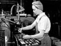 Une machiniste ajuste un tour d'atelier utilisé pour la fabrication de fusils-mitrailleurs à l'usine de fusils-mitrailleurs Bren de la John Inglis Co 8 Apr. 1941