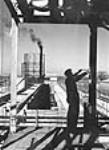 Un ouvrier de la construction prend des mesures au ruban à mesurer pendant la construction de l'usine Welland Chemical Apr. 1941
