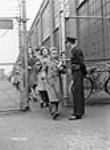 Des ouvrières des munitions quittent l'usine de fusils-mitrailleurs Bren de la John Inglis Co. sous l'oeil d'un gardien May 1941
