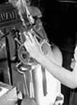 Une ouvrière tient une cigarette pendant qu'elle travaille sur des machines à l'usine de fusils-mitrailleurs Bren de la John Inglis Co 10 mai 1941