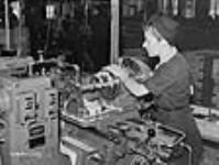 Woman machinist operates a lathe on a rifle part in a small arms plant, Long Branch juil. 1941