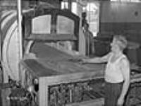 Un ouvrier enlève les canons de fusil chauds d'un four dans une usine d'armes légères à Long Branch juil. 1941