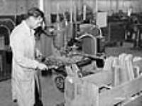 Un ouvrier surveille une machine façonnant des canons de fusil dans une usine d'armes légères à Long Branch juil. 1941