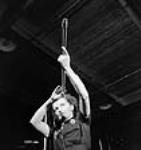 Une employée vérifie le viseur d'un fusil en mirant son canon à l'usine de la Small Arms Ltd. à Long Branch 26 mai 1942