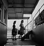 Two female Dominion Arsenals Ltd. munitions plant workers cross the river to Québec by ferry 24 Aug. 1942