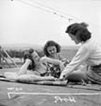 Des ouvrières des munitions canadiennes françaises de la Dominion Arsenals Ltd. profitent d'une journée de repos pour prendre un bain de soleil 24 Aug. 1942