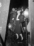 À Vancouver, une invitée d'honneur recule pour éviter les éclaboussures de champagne lors de la cérémonie de lancement du 100e navire de charge Dec. 1942