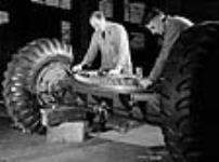Workmen fit the traversing rack to the bottom bracket under-structure of the 5.5-inch field gun carriage at the National Railways Munitions Ltd. plant 9 févr. 1943