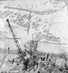 Des ouvriers construisent l'entrée basse de la galerie B au moyen d'un derrick lors du projet d'aménagement hydroélectrique de Shipshaw Jan. 1943