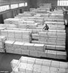 Un ouvrier, Gerald Newman, inscrit au pochoir des numéros d'identification sur des boîtes d'expédition, au service d'expéditions de l'Alcan Aluminium Limitée janv. 1943