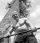 Le bûcheron finlandais Ollie Brackoos pose avec sa hache devant un arbre Apr. 1943