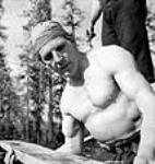 Finnish lumberman Ollie Brackoos poses lifting a plank of wood avril 1943