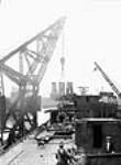 Une grue portuaire de quatre-vingts tonnes charge des assemblages de chaudières et de moteurs dans un navire en cale sèche dans un chantier naval de Montréal Summer 1943