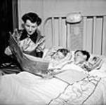 À  l'heure du coucher Mme Jack Wright lit une histoire à ses deux fils, Ralph et David Sept. 1943