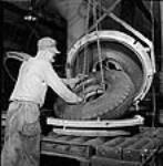 À l'usine Société Polymer Limitée, un ouvrier retire un pneu de caoutchouc synthétique du four de vulcanisation oct. 1943