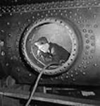 À l'intérieur d'une chaudière de locomotive X/Dominion pour expédition en Inde, un ouvrier se sert d'un pistolet à riveter Nov. 1943