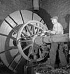 Un ouvrier règle un mécanisme sur une roue d'une locomotive X-Dominion pour expédition en Inde nov. 1943