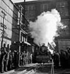 Une foule acclame et salue pendant l'essai de fonctionnement de la première locomotive 150 X-Dominion destinée à l'Inde. Le vétéran ingénieur d'essai Joseph Megin de Montréal (Québec) est aux commandes Nov. 1943