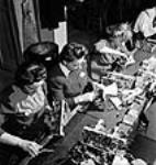 Female workers Gladys Nicholas, Isabel French and Betty Hill complete the receiver and transmitter wiring for army wireless units at the Addison Industries Ltd. plant 1944