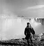 Horseshoe Falls, Canadian side of Niagara Falls, with Reggie Thompson of Hamilton, New Brunswick, on guard. Falls are protected by barbed wire and military guard Mar. 1944