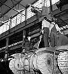 Des ouvriers descendent un canon de 25 livres pour l'installer sur un obusier automoteur de la société Montreal Locomotive Works Summer 1943