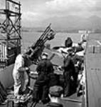 Des ouvriers installent des canons jumeaux Oerlikon à la place d'un seul canon Oerlikon pendant la modification de porte-avions au quai Lapointe du chantier naval de Burrard mai 1944