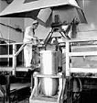 L'ouvrier D. Thériault remplit un cône de charge de torpille d'explosifs aux usines Cherrier et Bouchard de la société Defense Industries Ltd July 1944