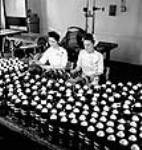 [Mmes Y. Morin et M. Rose cémentent des obus de 25 livres à l'usine Defence Industries Ltd. de Montréal (Québec).] June 1944