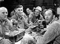 Des ouvriers de la Société Asbestos au moment de leur déjeuner, assis à des tables fournies par l'entreprise July 1944