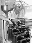 Le chef du laboratoire Charles Webb effectue un essai pour déterminer le pourcentage de chaque longueur de fibre contenue dans un échantillon d'amiante à l'usine Johns-Mainville Canada Inc June 1944