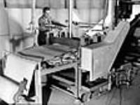 L'ouvrier Armand Jutras conduit une machine à onduler d'épaisses feuillesde papier d'amiante utilisées pour envelopper les tuyaux à l'usine Johns-Mainville Canada Inc., Asbestos (Québec) juin 1944