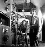 À l'usine RCA Victor, (à gauche) le sergent Peter Degenstein, de North Battleford (Sasketchewan), et Victor Isaac effectuent les derniers ajustements et essais sur des émetteurs à moyenne portée avant leur expédition juil. 1944