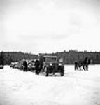 View of a truckhaul hauling sleighs loaded with logs across a frozen lake surface mars 1943