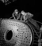 Two male rivetters operating a rivetting gun on the firebox of an X-Dominion locomotive destined for India nov. 1943