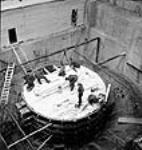 Overhead view of workmen working on the scrole case of the No. 9 unit inside the powerhouse during the Shipshaw Power Development project janv. 1943