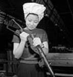 Agnes Wong, Chinese-Canadian munitions worker, adding a butt to the end of a gun at the John Inglis Company plant 10 avri1 1944