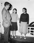 Alexander Stevenson, Officer in charge of the Eastern Arctic Patrol, speaking with Seeya (E7-58) and Ninquapik (E7-103), Inuit girls who are returning to Lake Harbour [Kimmirut (formerly Lake Harbour), Nunavut] aboard C.G.S. C.D. Howe after medical treatment in southern Canada 1950