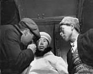 Dr. Walter Crewson examines the eyes of an Inuit woman in one of the holds of R.M.S. Nascopie. Lidlout, an Inuit interpreter, watches the examination August 1946
