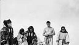 Richard Finnie [second from right, sunbathing] and Inuit driving dogs 1931