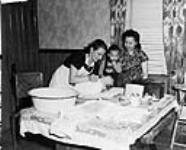 Nurse Frieda Fortune bathes Kenneth Chan while Mrs. Fong K. Chan and Kenneth's brother Gene watch c 1950